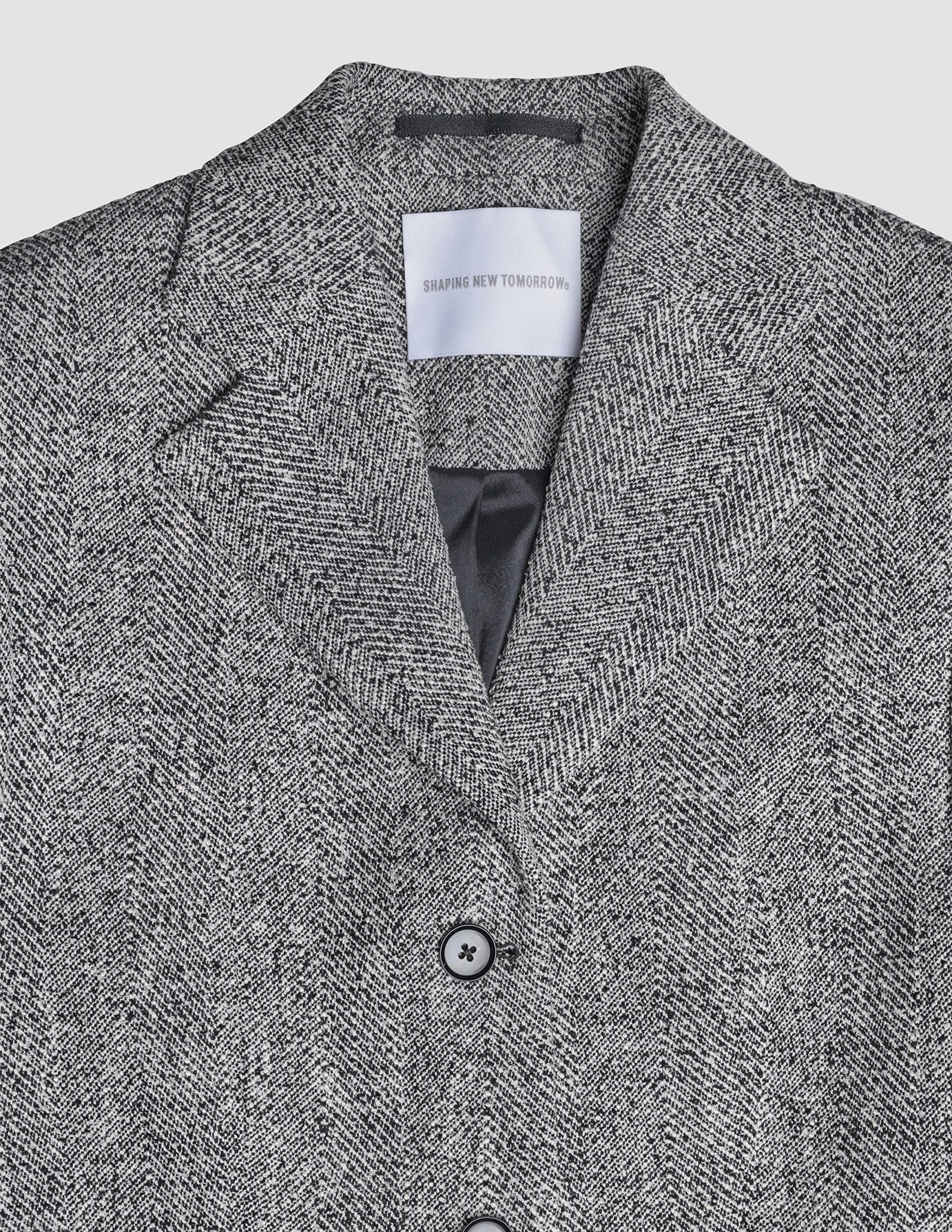Ashryn Blazer i Domino Herringbone, detaljebillede af jakke med knap og åbning.